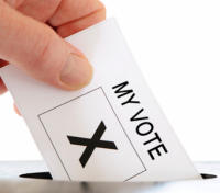 A hand placing a vote in a box